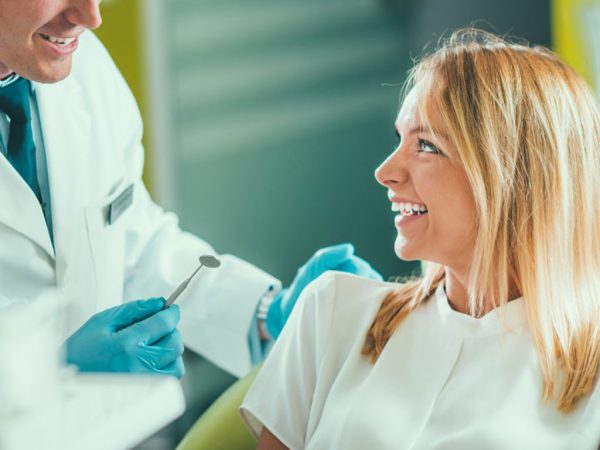 Woman smiling and receiving oral exam by dentist