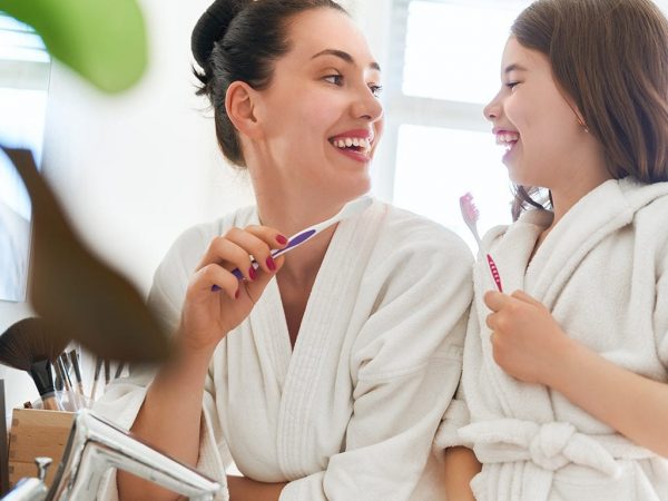 Mom and daughter Mom and daughter looking at each other smiling and holding toothbrush