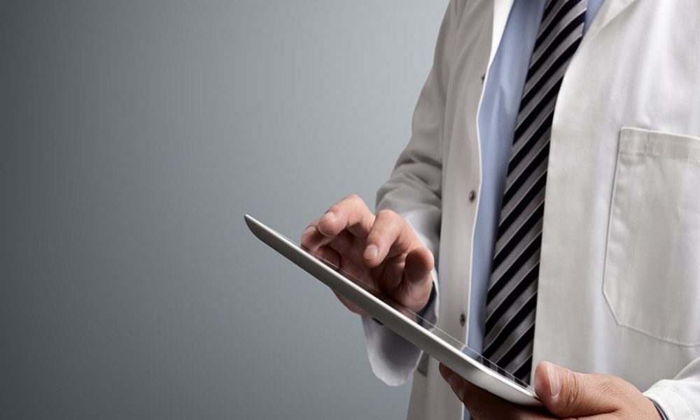 Doctor in lab coat and stripped tie working on tablet