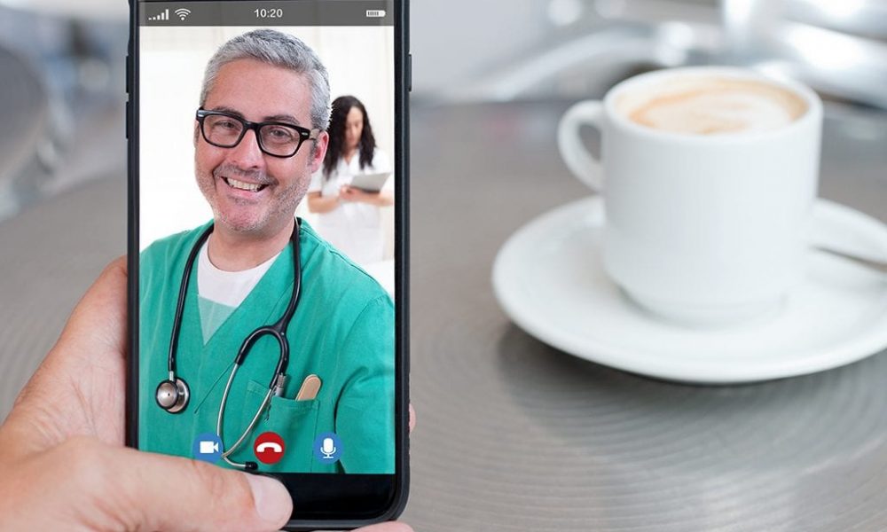 Doctor in green scrubs on smartphone for telemedicine