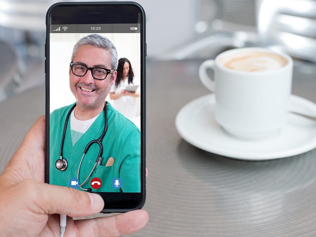 Doctor in green scrubs on smartphone for telemedicine