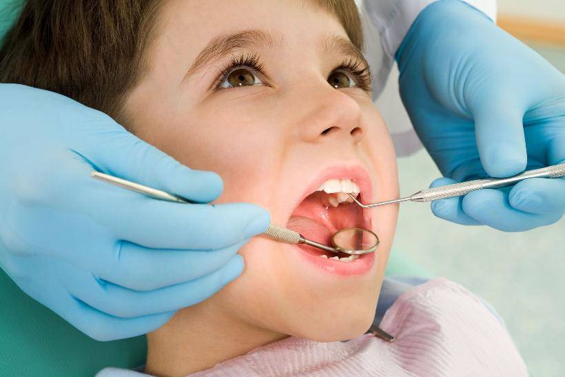 Young kid receiving dental exam by a technician with gloves on