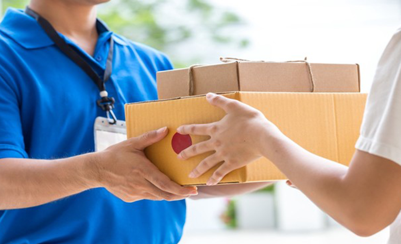 Delivery man in blue shirt handing packages over to a woman in a white shirt