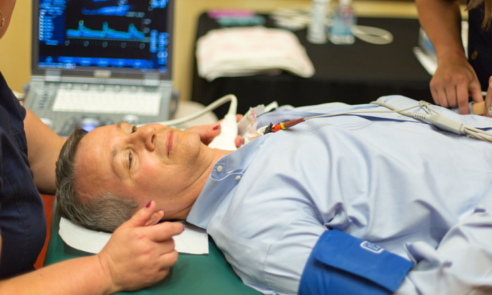 Man laying on a medical table receiving a carotid artery preventative health screening check via ultrasound