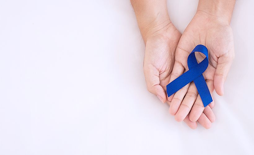 hands holding a blue colon cancer awareness blue ribbon