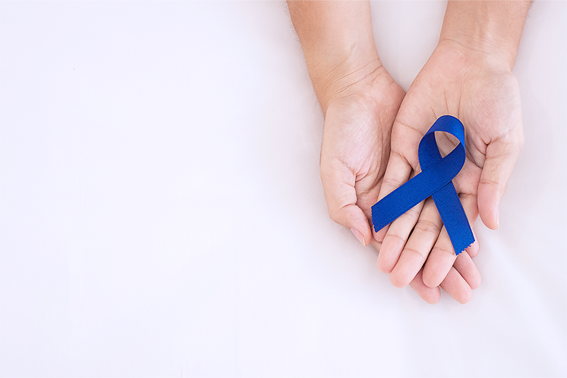 hands holding a blue colon cancer awareness blue ribbon
